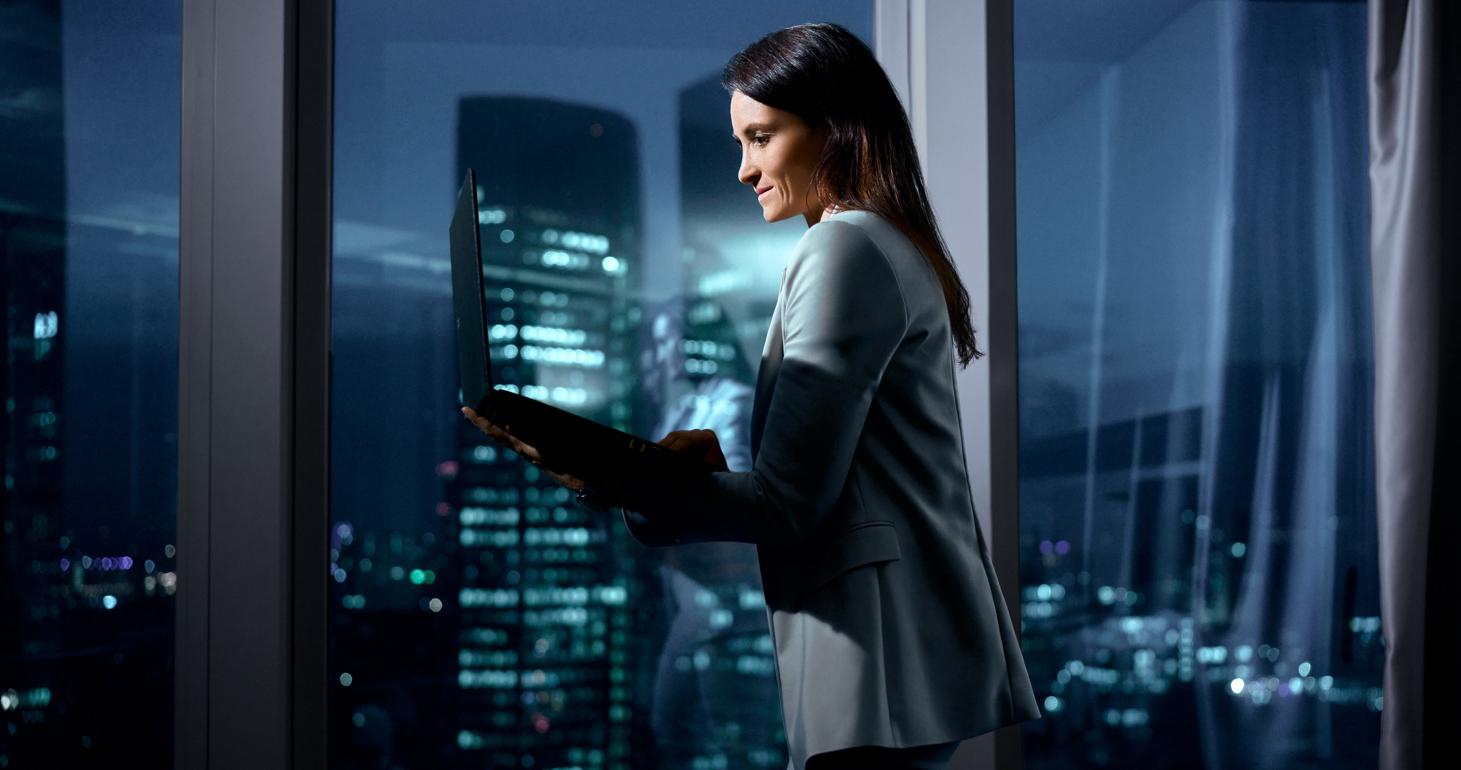Business-Portrait Frau mit Laptop und Skyline